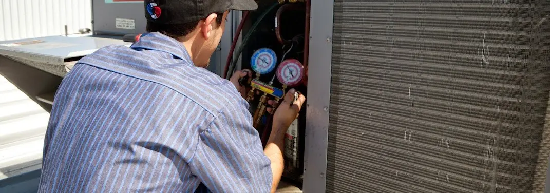 HVAC technician servicing a condenser unit in Georges